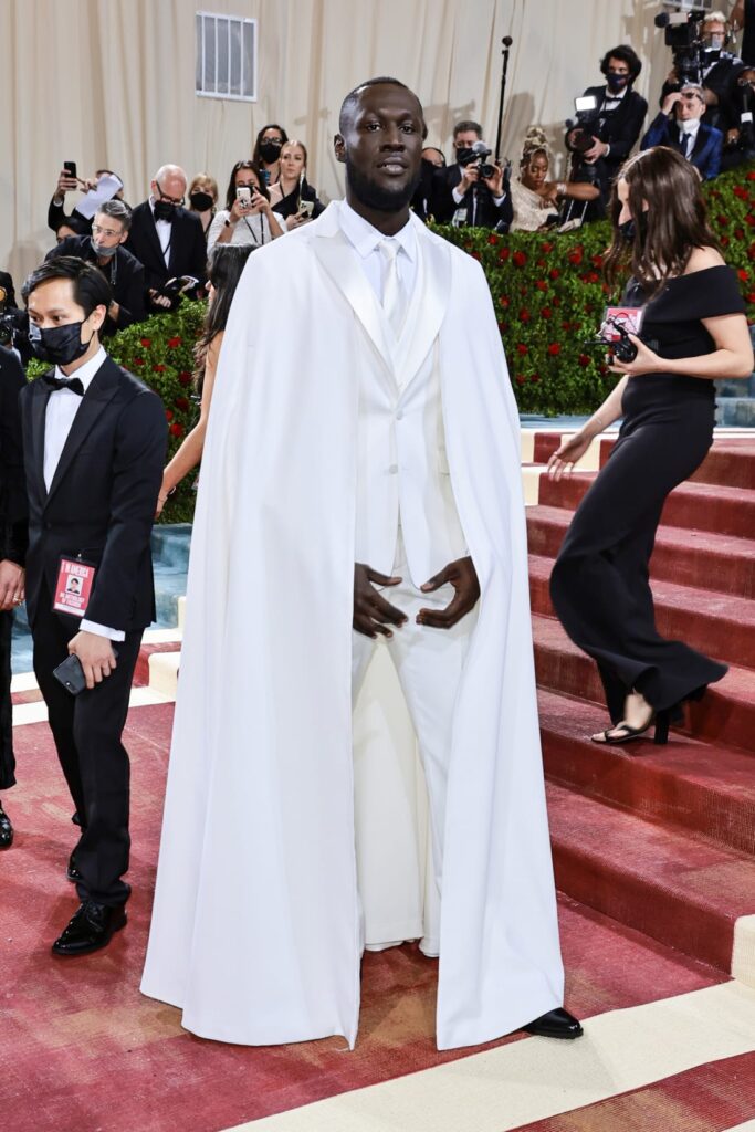Stormzy departed from his usual wardrobe of dark clothing for a pristine white caped look by Ricardo Tisci for Burberry. Credit: Jamie McCarthy/Getty Images
