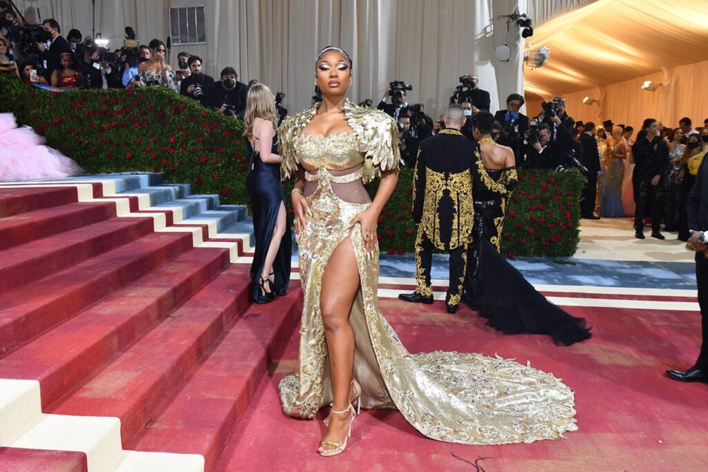 Megan Thee Stallion opted for a golden gown with sculpted feather-like shoulders by Moschino and attended the event alongside the brand's creative director Jeremy Scott. Credit: Angela Weiss/AFP/Getty Images